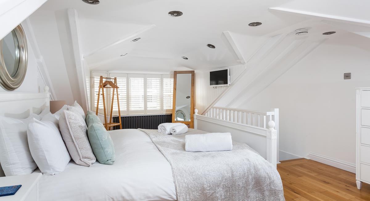 Bedroom 3 has a loft aspect with natural oak wood flooring, an easel mirror and a trestle style hanging rail.