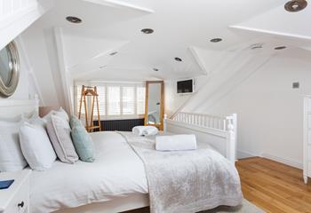 Bedroom 3 has a loft aspect with natural oak wood flooring, an easel mirror and a trestle style hanging rail.