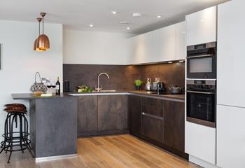 The kitchen is spacious, highly functional and features a selection of mod-cons. We love the copper lights and bar stools. 