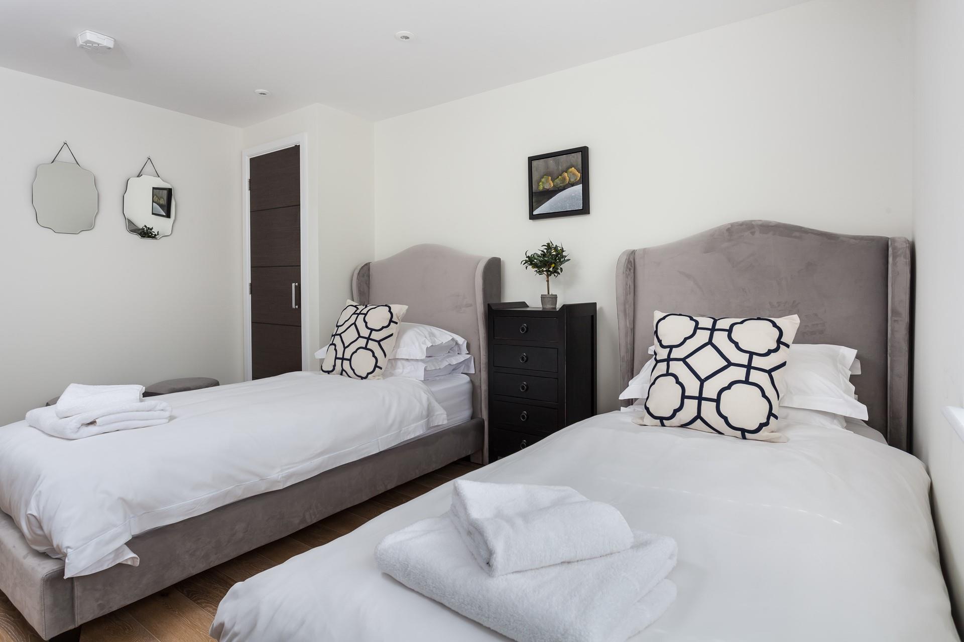 Velvet twin beds, crisp white linen and plump cushions create a relaxing space in bedroom 2. 