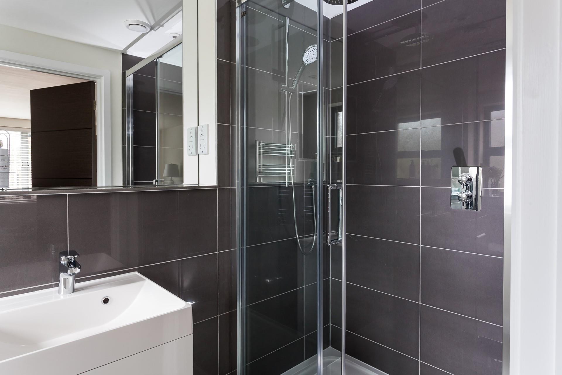 The modern shower features a rainfall showerhead with a separate handheld shower attachment.