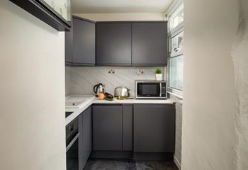 The compact kitchen is stylish and well-equipped for preparing and cooking meals.