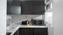 The compact kitchen is stylish and well-equipped for preparing and cooking meals.