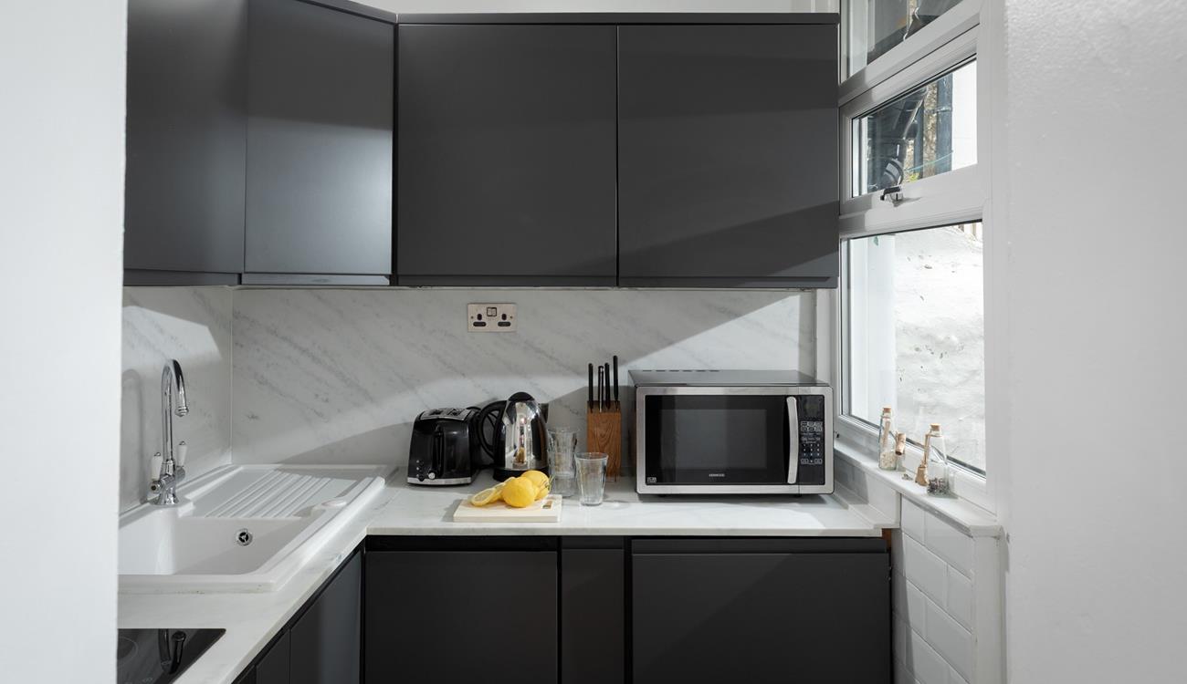 The compact kitchen is stylish and well-equipped for preparing and cooking meals.