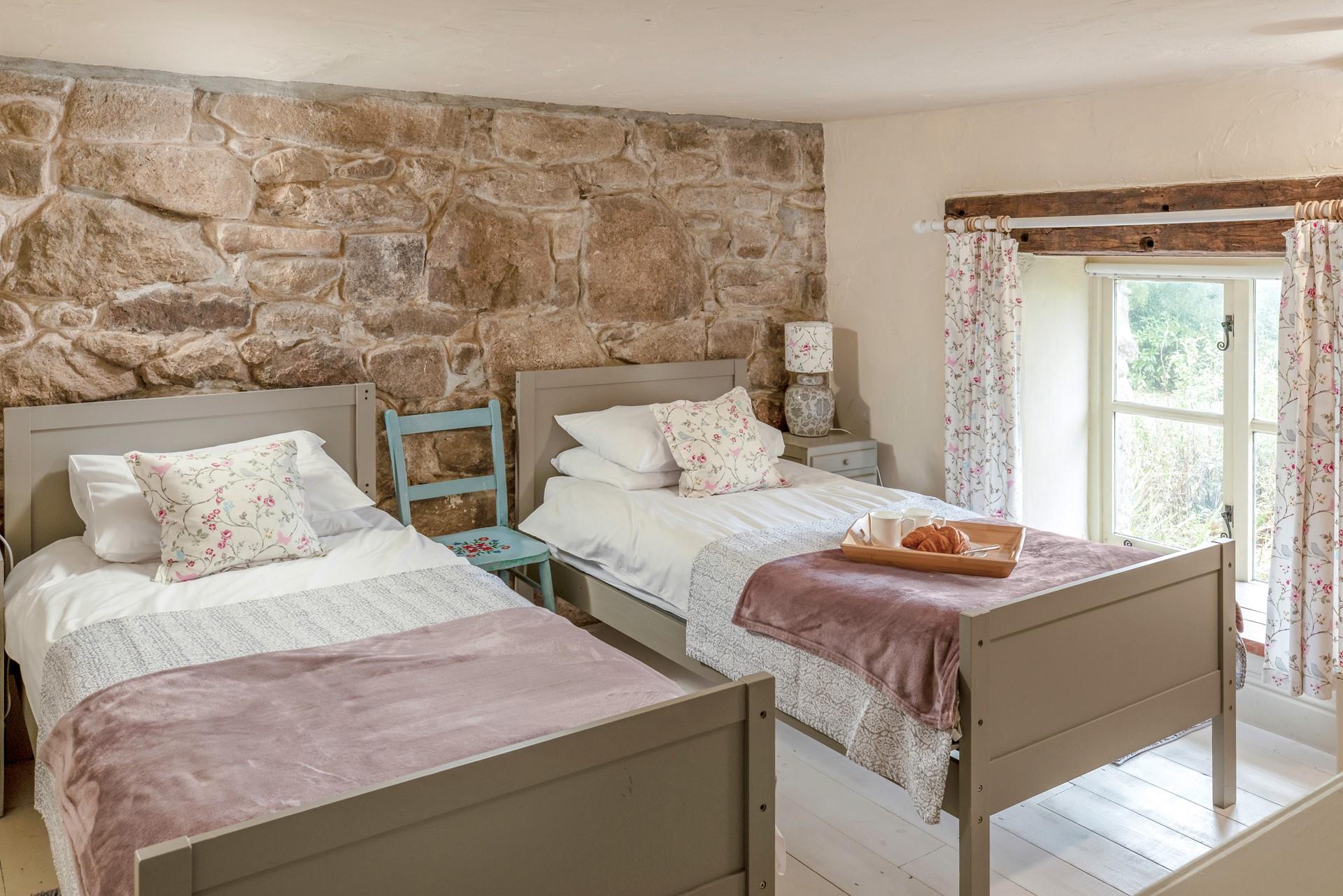 The first set of stairs lead from the kitchen diner lead you to this cosy twin bedroom. The stone wall is the perfect Cornish touch. 