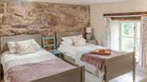 The first set of stairs lead from the kitchen diner lead you to this cosy twin bedroom. The stone wall is the perfect Cornish touch. 