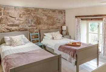 The first set of stairs lead from the kitchen diner lead you to this cosy twin bedroom. The stone wall is the perfect Cornish touch. 