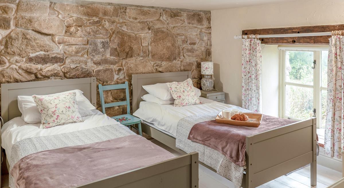 The first set of stairs lead from the kitchen diner lead you to this cosy twin bedroom. The stone wall is the perfect Cornish touch. 