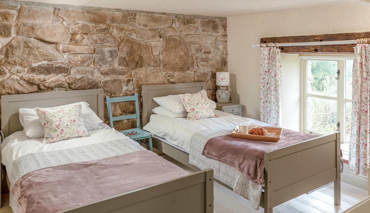 The first set of stairs lead from the kitchen diner lead you to this cosy twin bedroom. The stone wall is the perfect Cornish touch. 