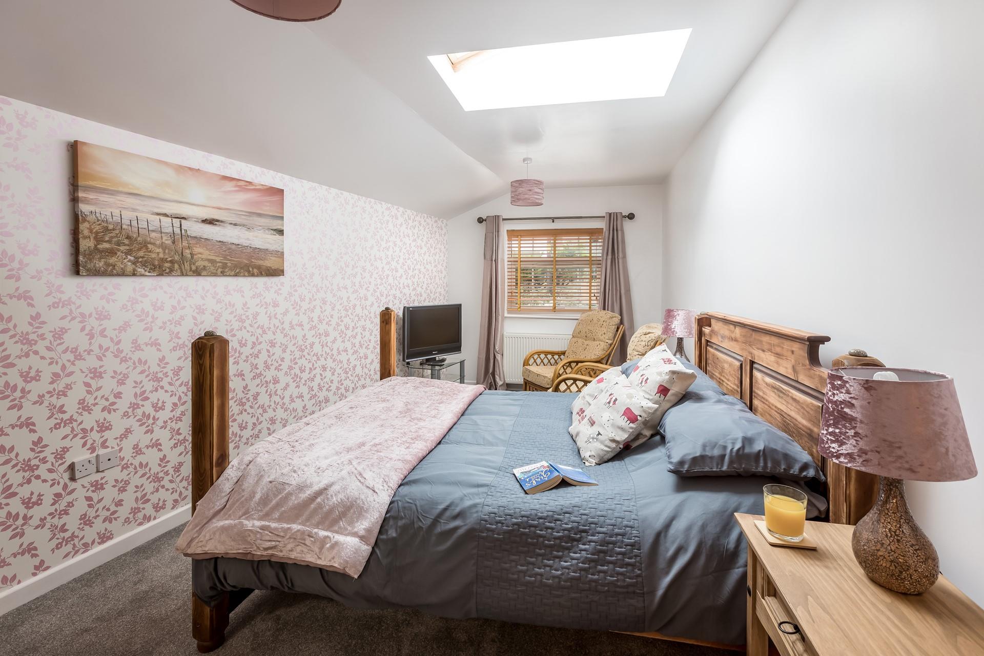 Bedroom 1 is homely featuring coastal artwork and colourful wallpaper.