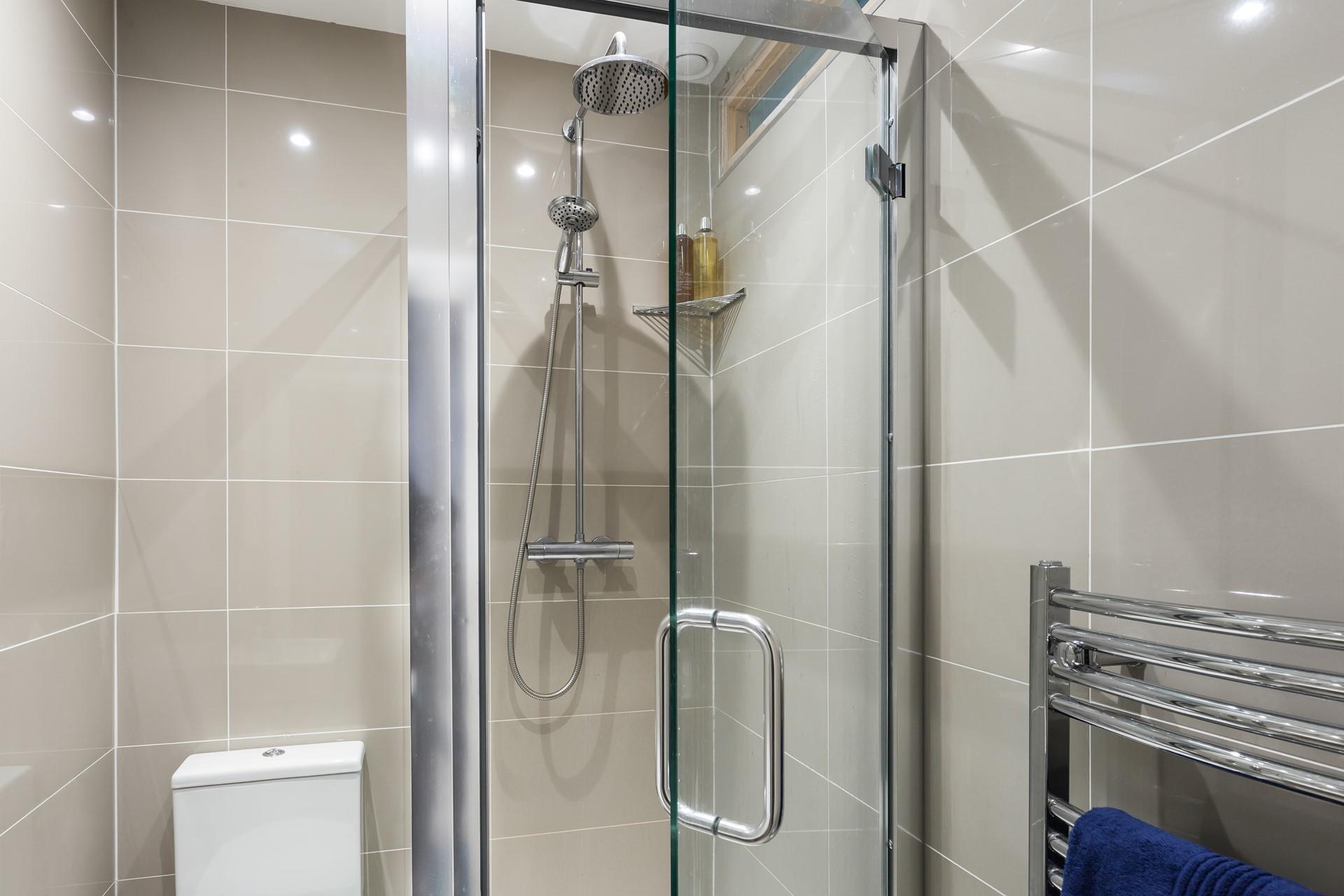 The modern shower room features a large rainfall shower head and a separate shower attachment. 