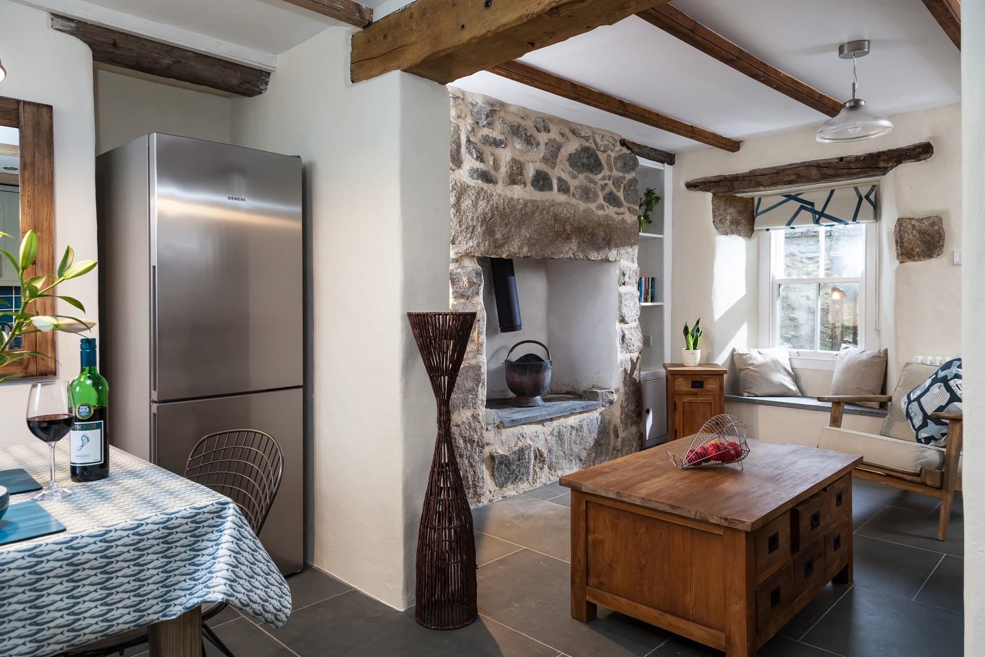 The open plan living-kitchen area features a beautifully crafted wooden chest table, perfectly complimenting the granite feature fireplace.