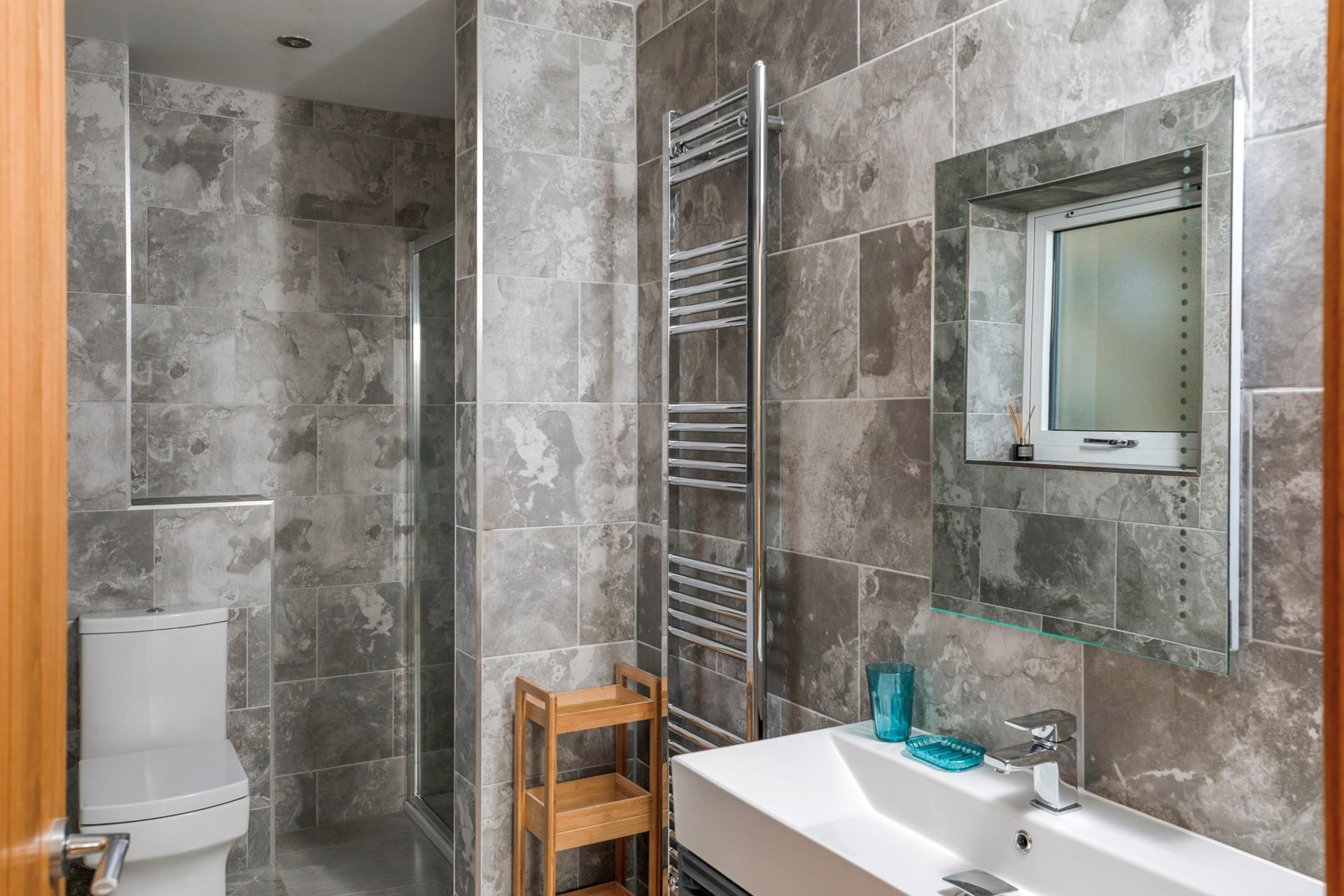 The marble effect tiles and modern fixtures give the ensuite an indulgent, spa-like feel.