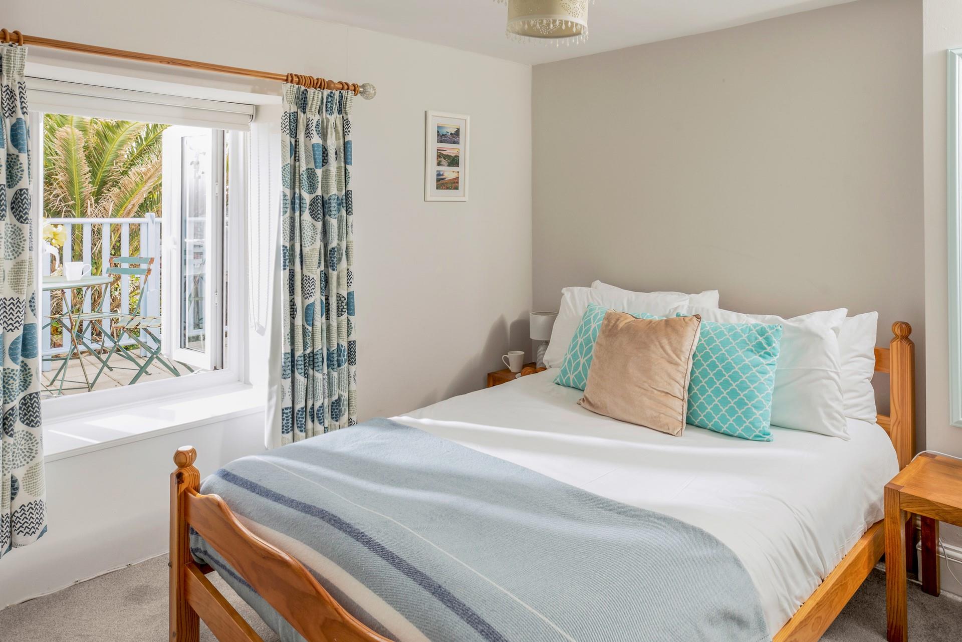 Bedroom 4 with comfortable double bed, looks out onto the balcony and garden.