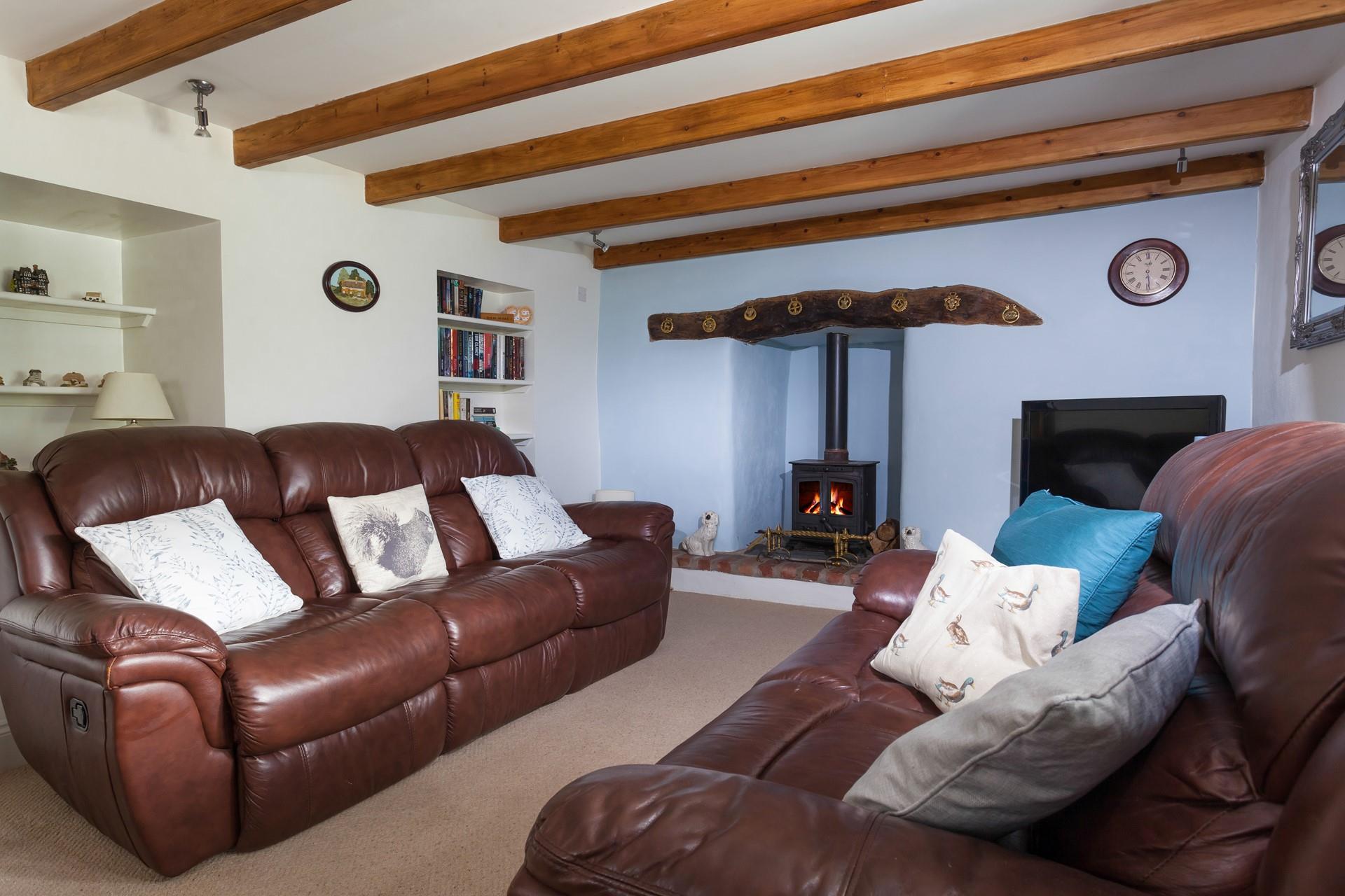 The second living area with its classic leather sofas and cosy woodburner is a great space to snuggle up.