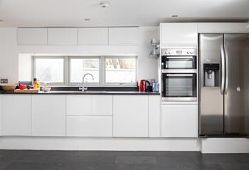 The kitchen is sleek with modern gadgets and a large fridge freezer, perfect for guests who love to cook.
