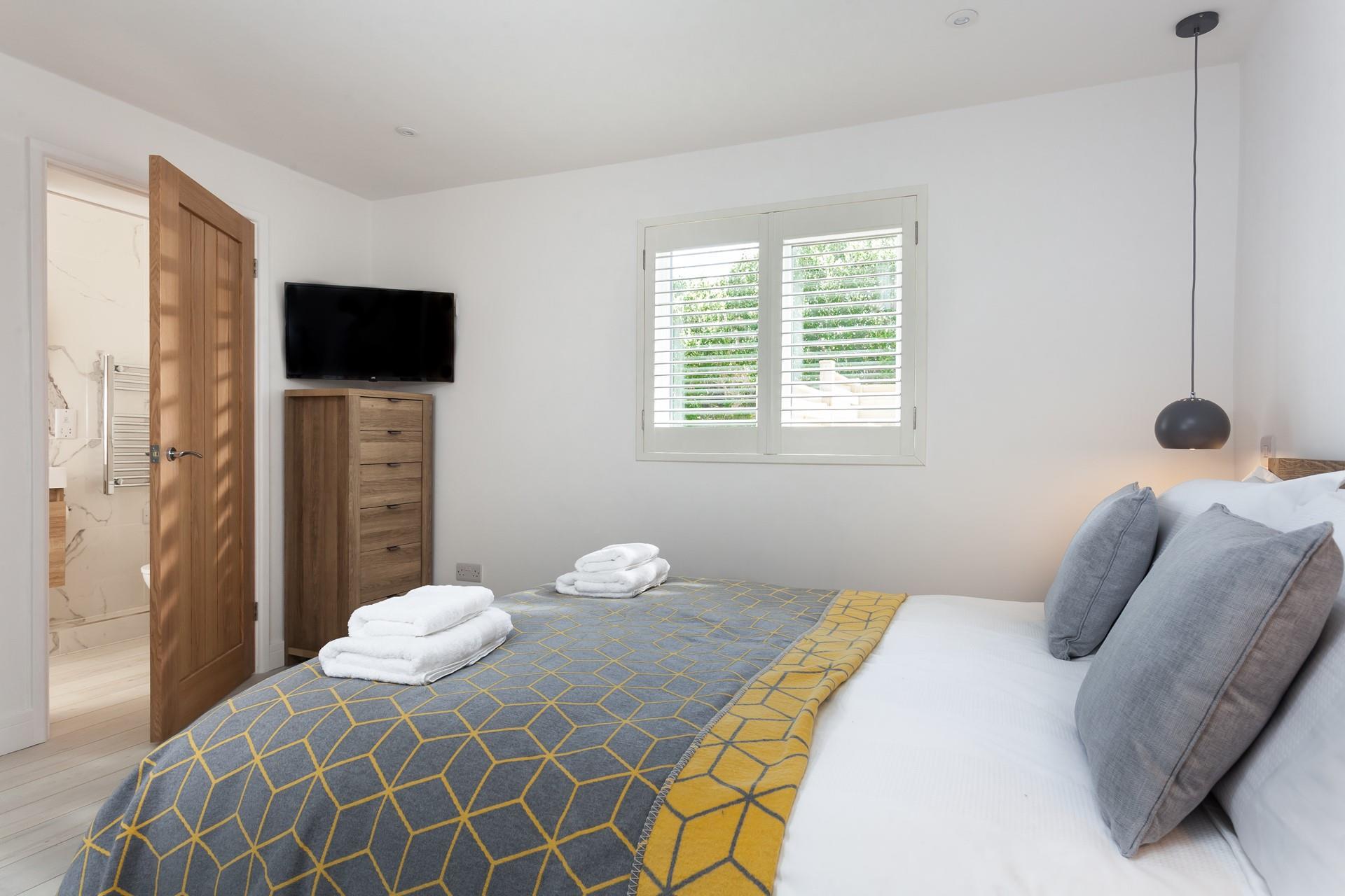 The cosy bedroom boasts a TV and stylish en suite.