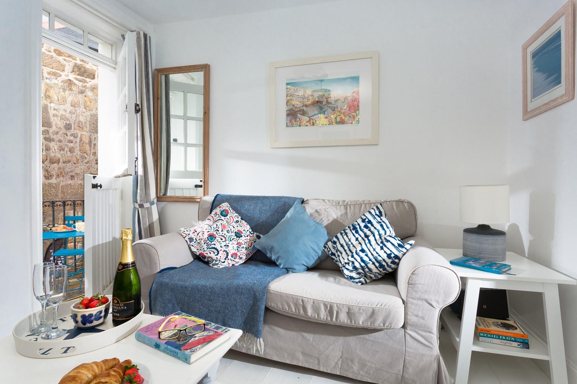 The bright and airy living room is decorated in calming coastal tones with stable doors opening to the outside.