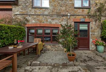 The rose garden courtyard is shared with the neighbouring cottage but has its own natural area bordered with potted plants and hedging.