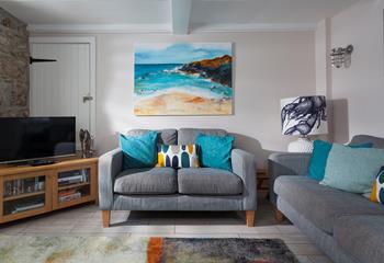 Beautifully finished with bold blues and striking coastal artwork, the sitting room echoes Trelither's seaside location. 