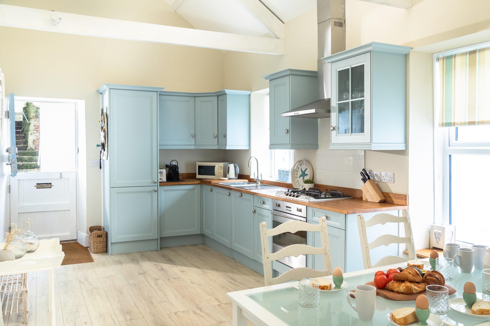 The light and airy kitchen area is well-equipped for preparing meals to dine in with family and friends. 