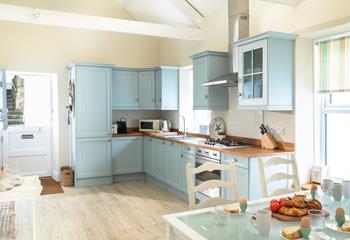 The light and airy kitchen area is well-equipped for preparing meals to dine in with family and friends. 