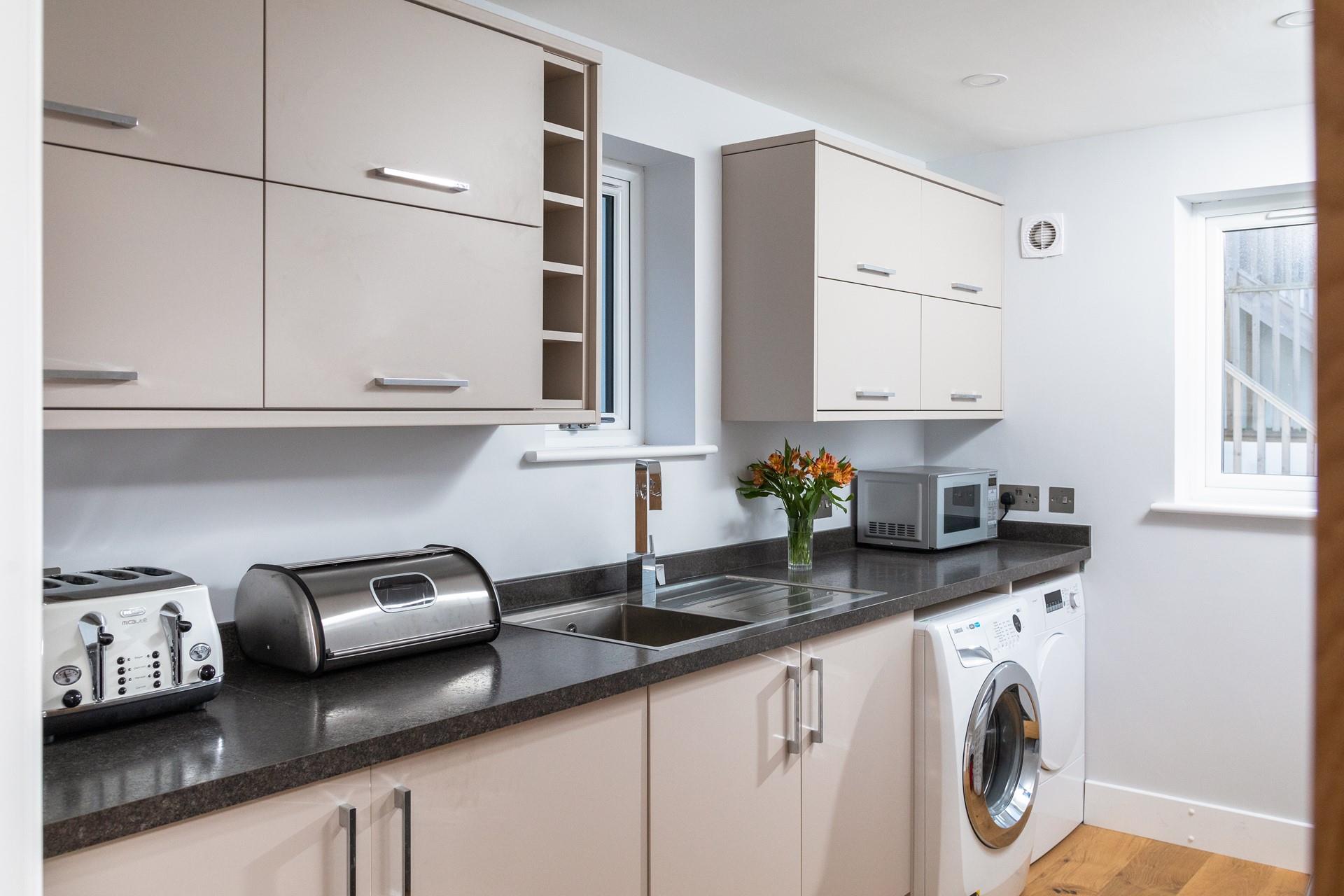The utility room is well-equipped including a washing machine, tumble dryer, microwave and sink.