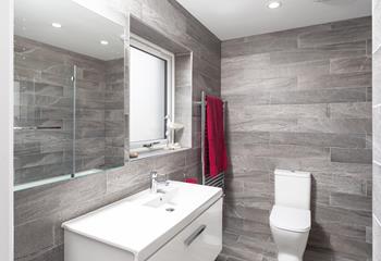 The family bathroom has stylish tiles and a light-up mirror for getting ready.