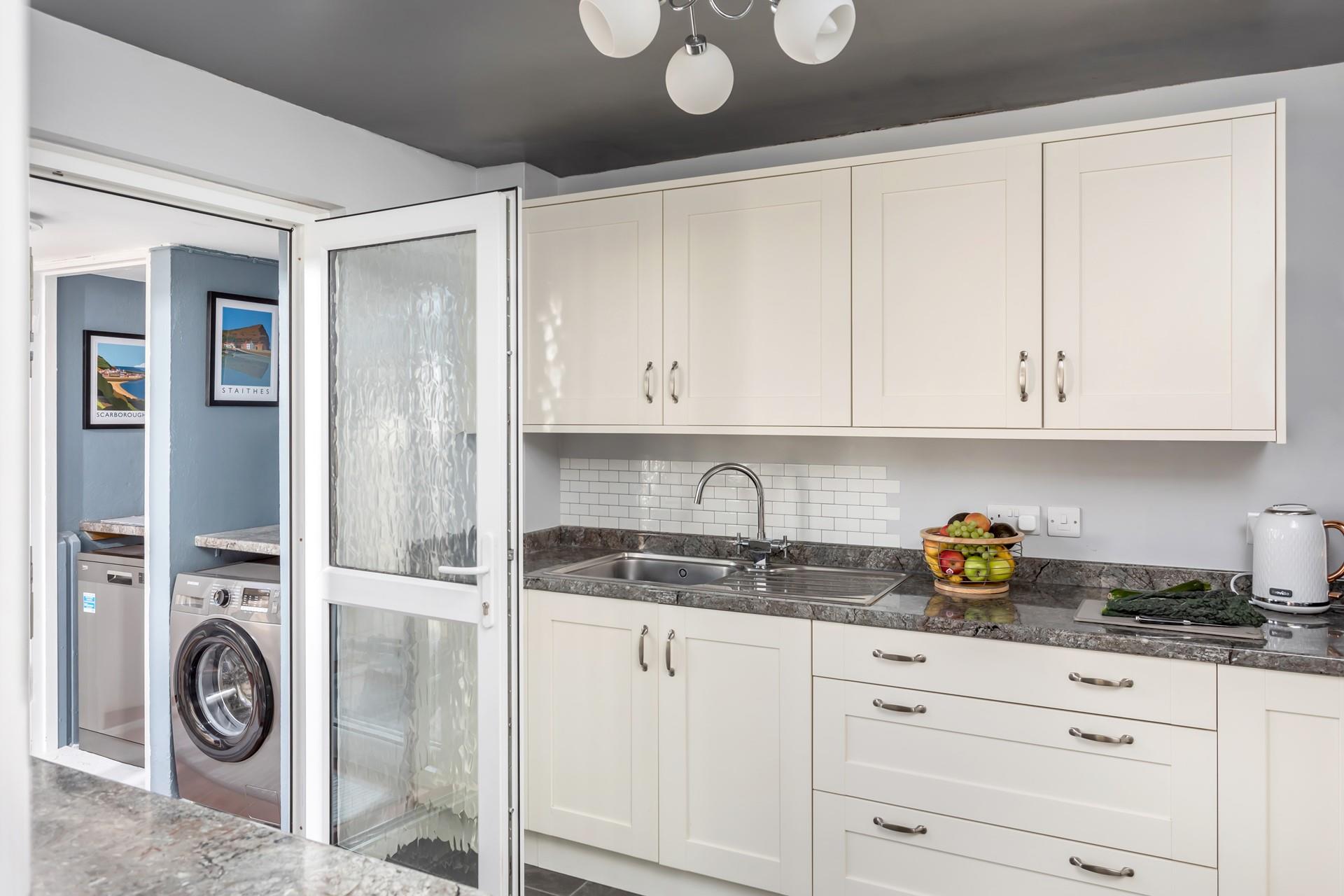 The kitchen leads into the utility room, which has a washing machine and dishwasher. 