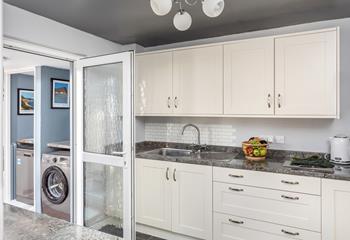 The kitchen leads into the utility room, which has a washing machine and dishwasher. 