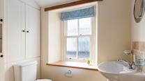 The character of the cottage continues into the family shower room, with an exposed beam and a deep window sill. 