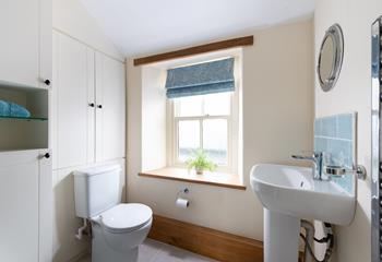 The character of the cottage continues into the family shower room, with an exposed beam and a deep window sill. 