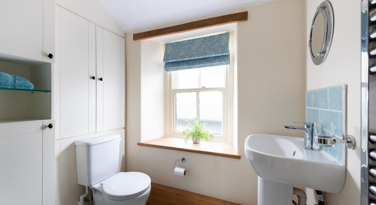 The character of the cottage continues into the family shower room, with an exposed beam and a deep window sill. 