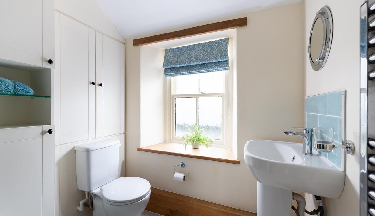 The character of the cottage continues into the family shower room, with an exposed beam and a deep window sill. 