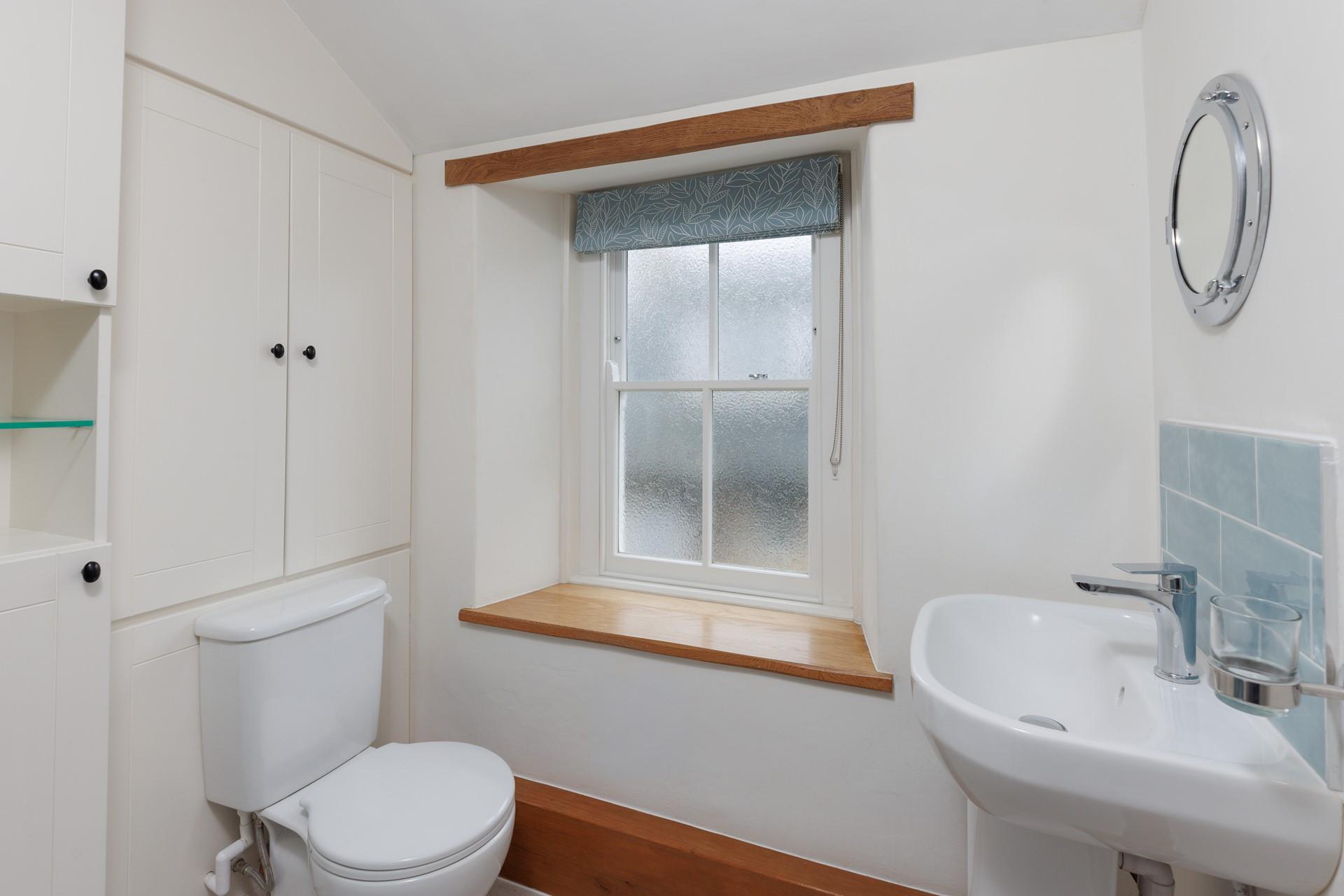 The character of the cottage continues into the family shower room, with an exposed beam and a deep window sill. 
