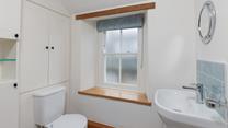 The character of the cottage continues into the family shower room, with an exposed beam and a deep window sill. 
