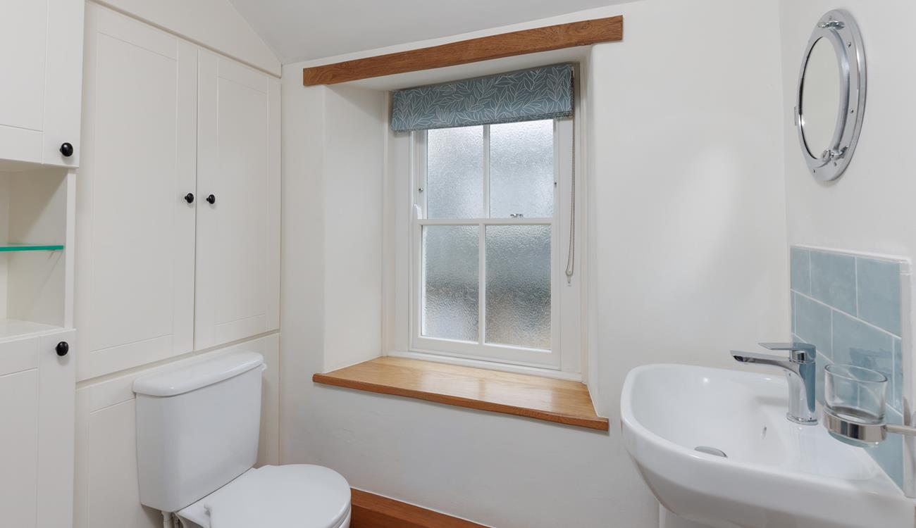 The character of the cottage continues into the family shower room, with an exposed beam and a deep window sill. 