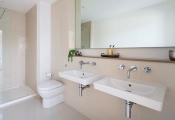 Twin sinks add a touch of luxury to the en suite shower room, which is complete with a rainfall shower. 