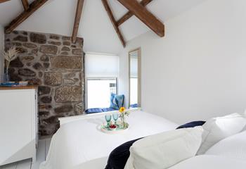 Exposed beams and a feature granite wall add character to this relaxing bedroom. 