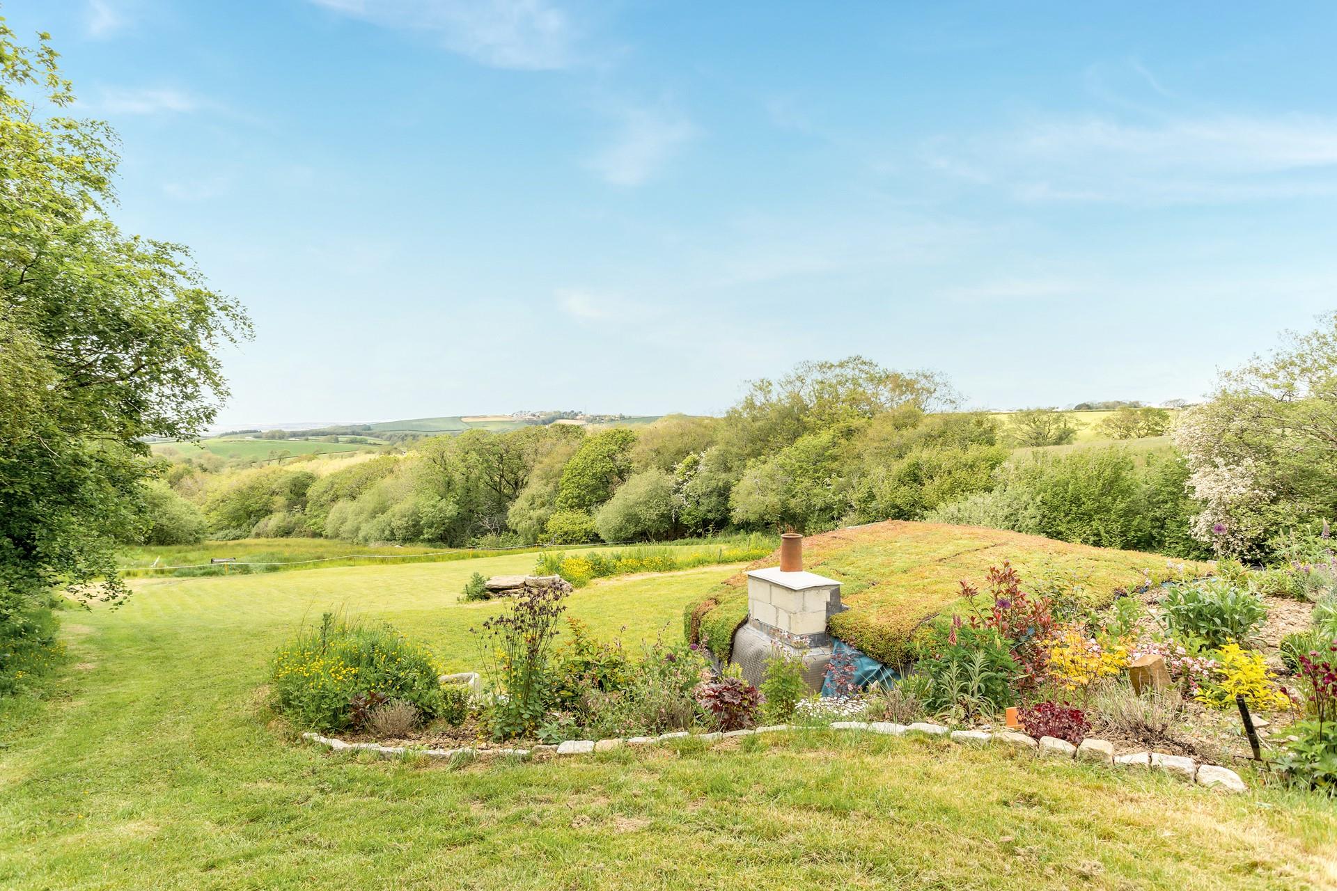 The garden area has a quirky hobbit house, perfect for enjoying the countryside views.