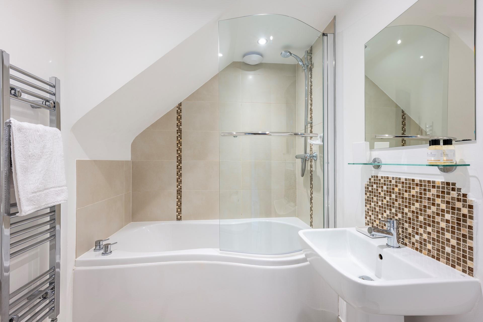 The sleek bathroom benefits from both a bath and shower.