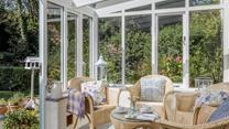 The sunny conservatory leads down to a quaint stream.