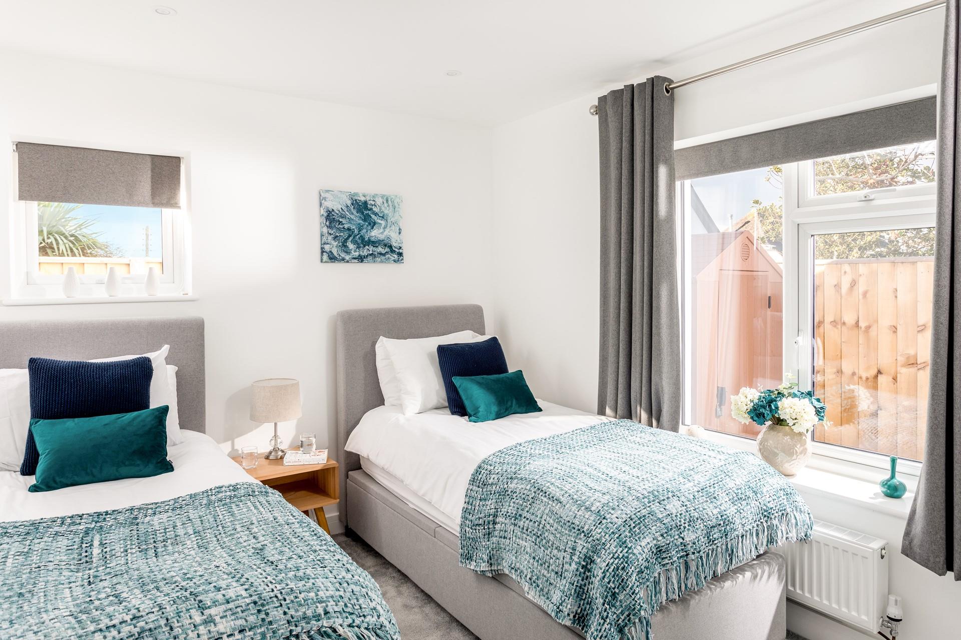 Bedroom 2 has twin beds and a calming seaside colour decor, perfect for adults or children.