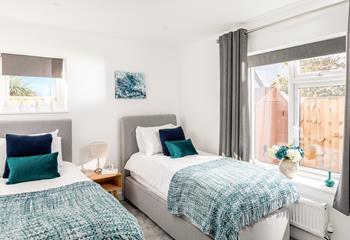 Bedroom 2 has twin beds and a calming seaside colour decor, perfect for adults or children.