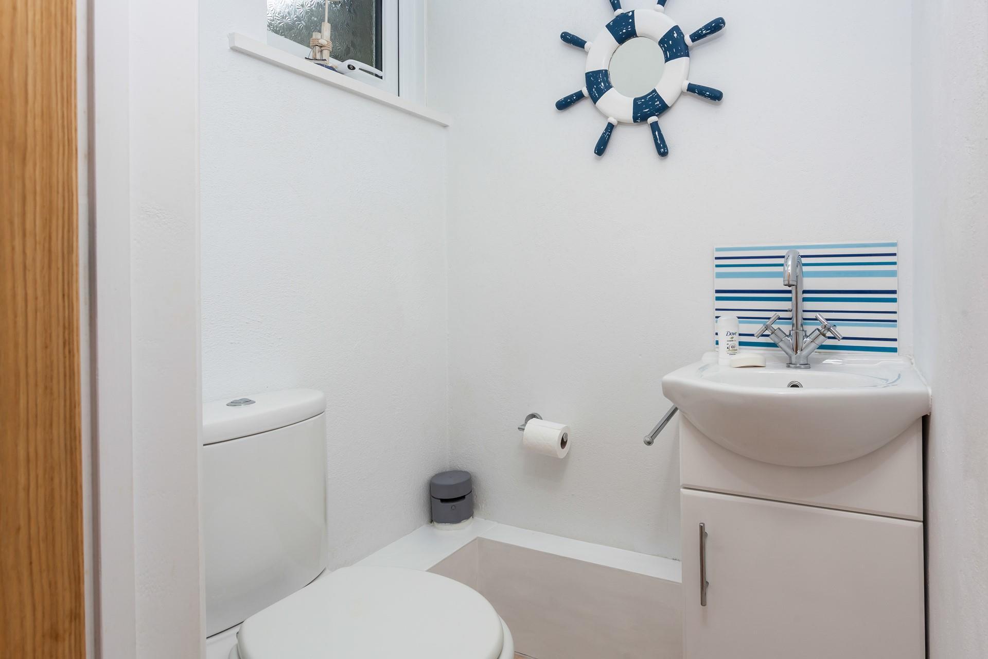 The downstairs cloakroom has a WC and basin and is decorated with a blue and white theme.