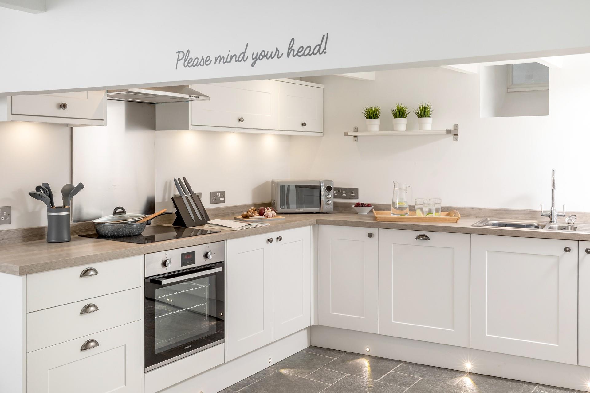 The modern kitchen features lots of lighting and is stylishly finished.