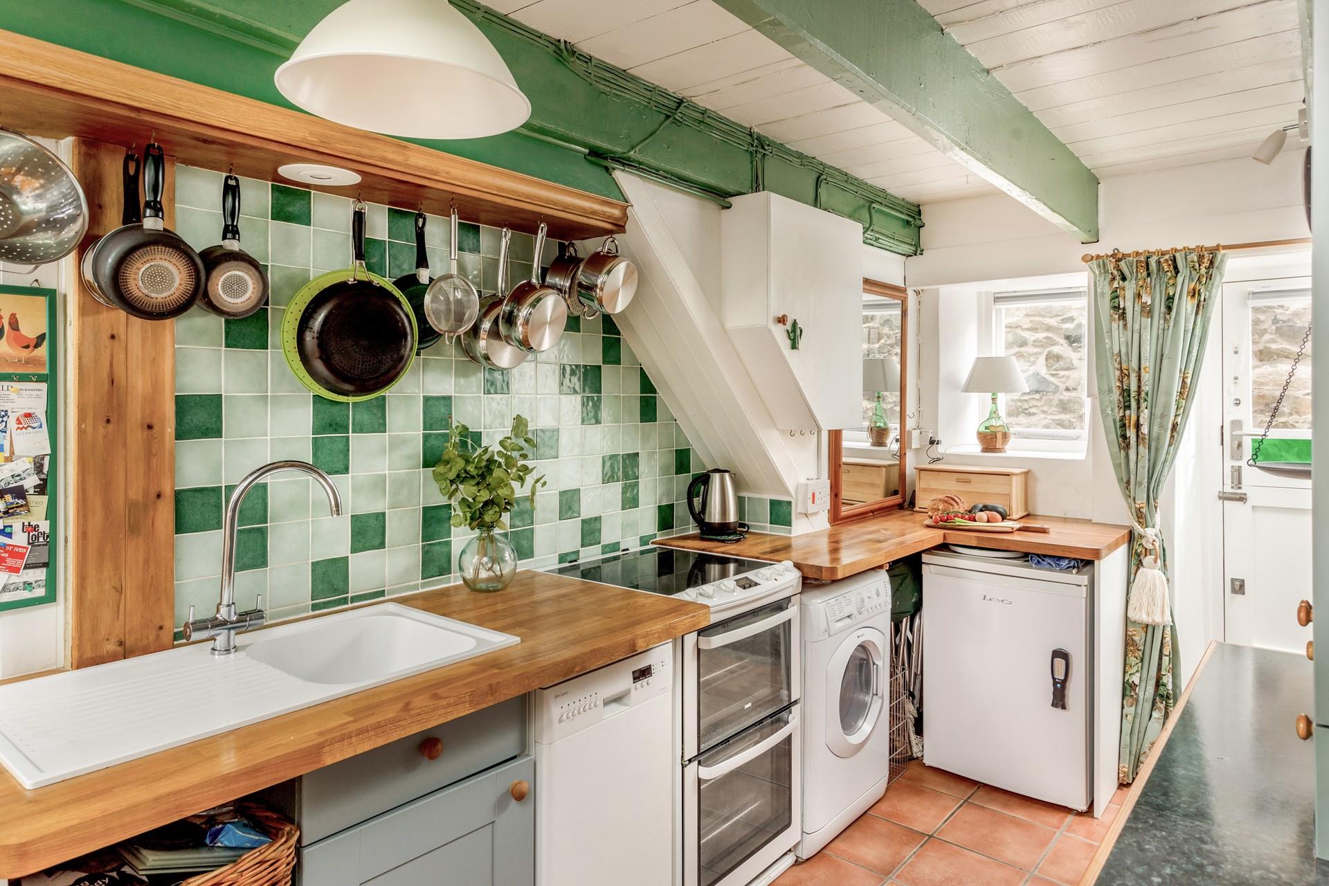 The kitchen has green tiles and is in keeping with the cottage feel.