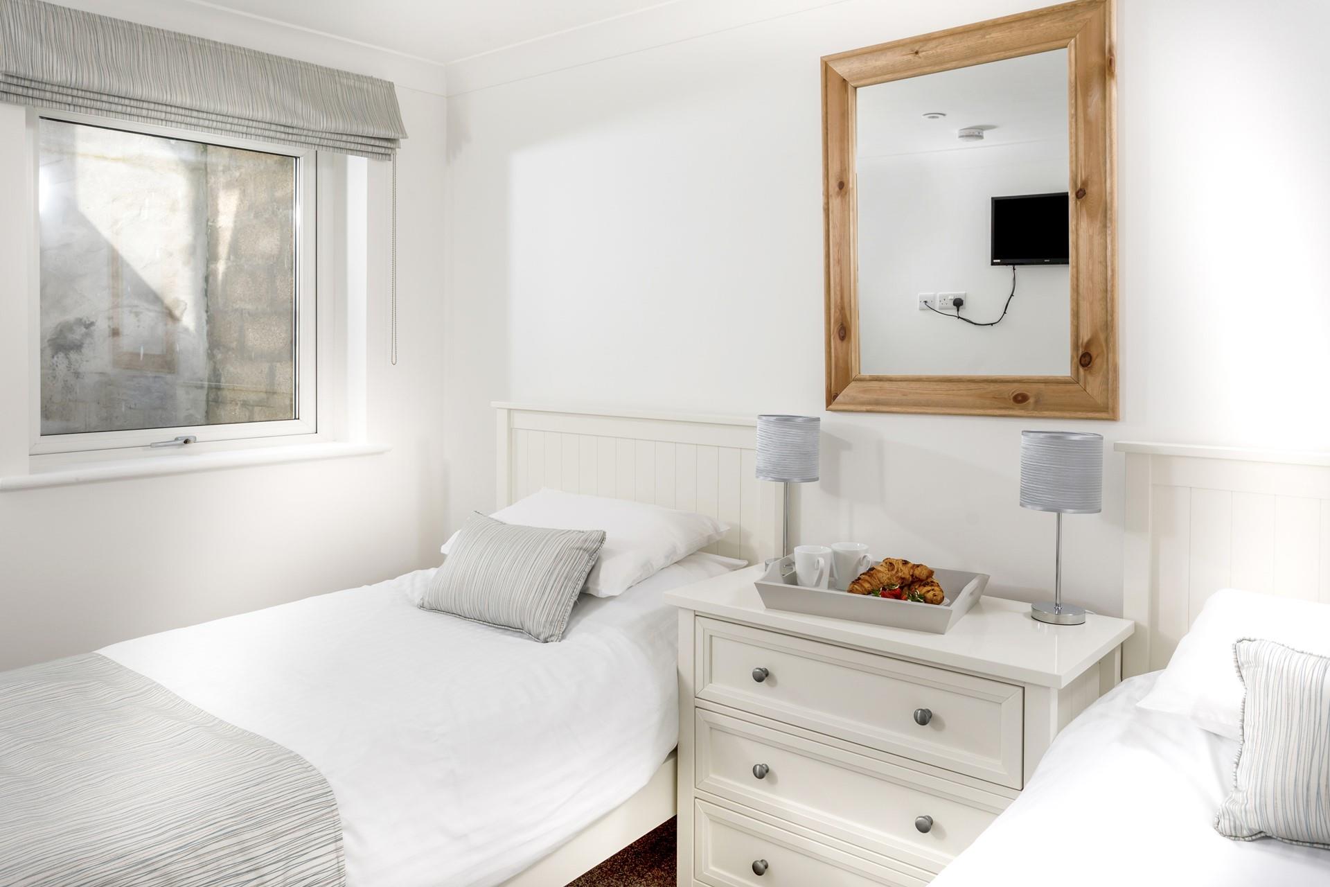 The twin room has stylish furnishings including a chest of drawers and two bedside lamps.