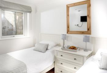 The twin room has stylish furnishings including a chest of drawers and two bedside lamps.