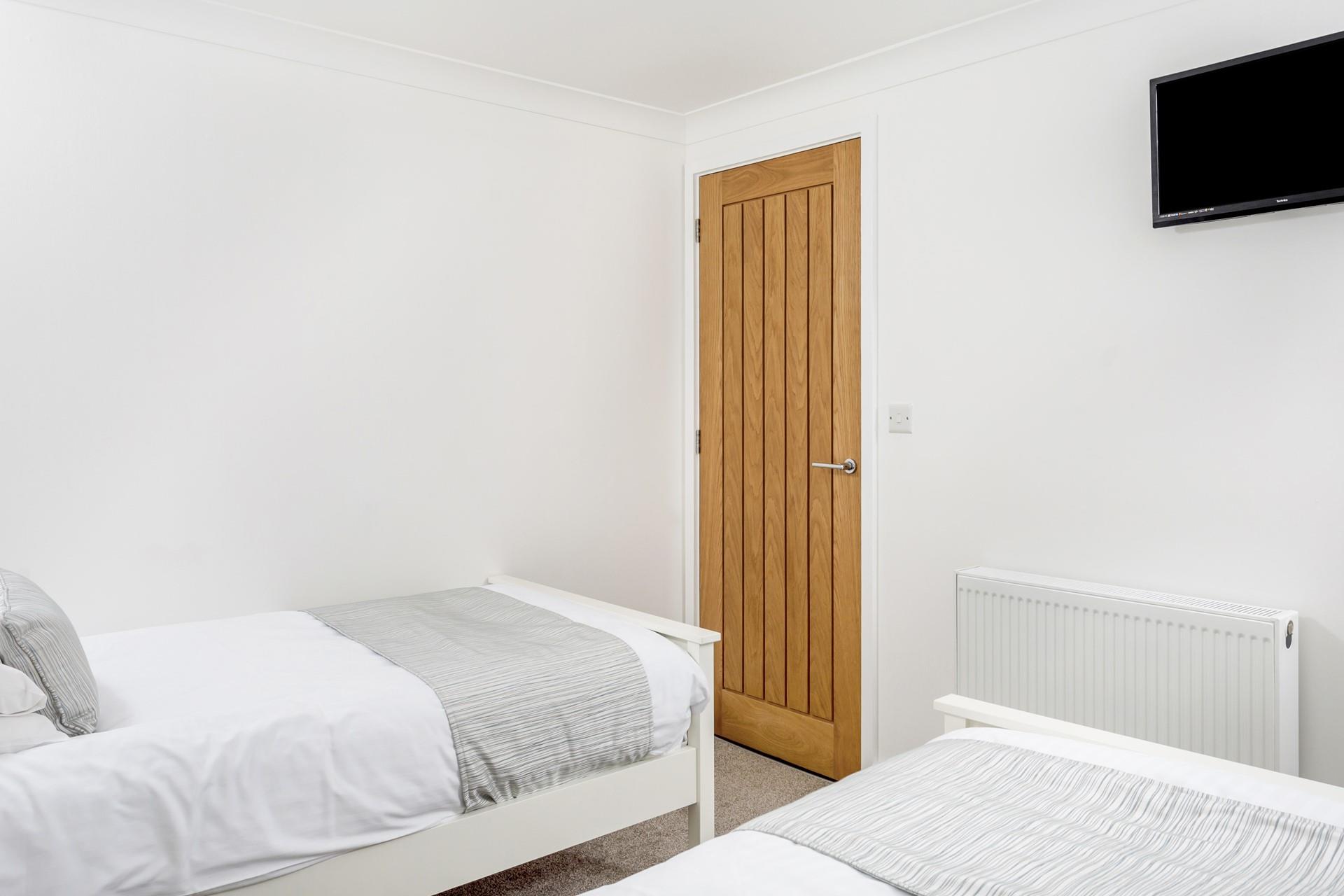 Bedroom 2 has comfortable twin beds and bright white walls.